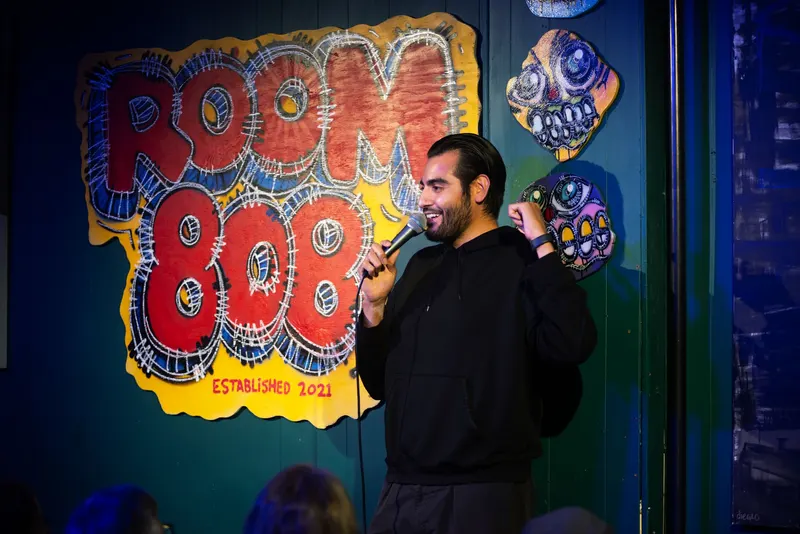 A comic laughing on stage at Room 808